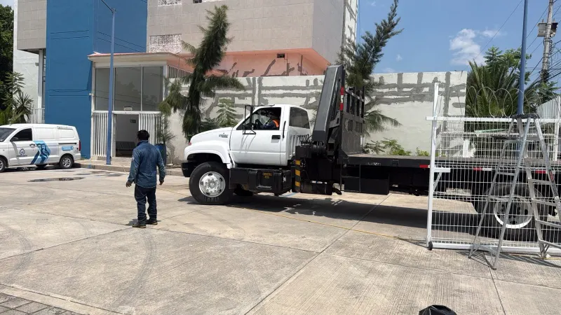 Camión con grúa articulada replegada, una escalera y paneles metálicos en el área de trabajo.